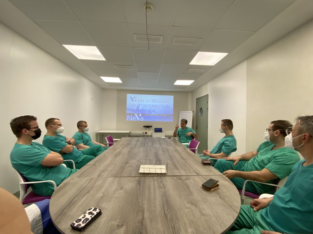 doctors sitting around a large table watching a NeVa demonstration on a screen